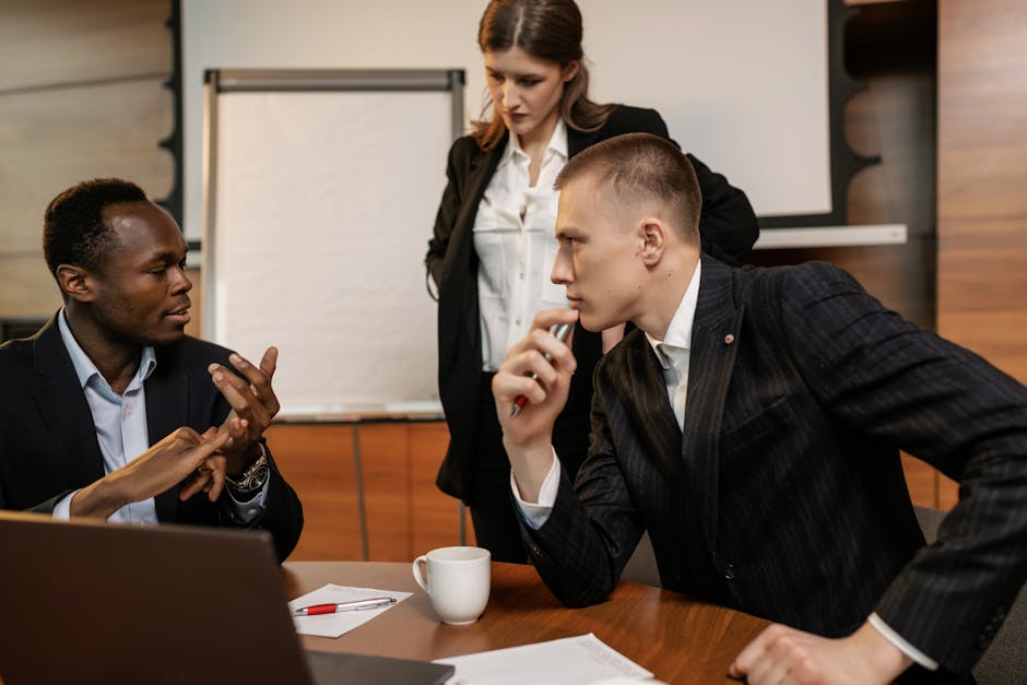 Diverse colleagues in active discussion around a conference table in a modern office setting